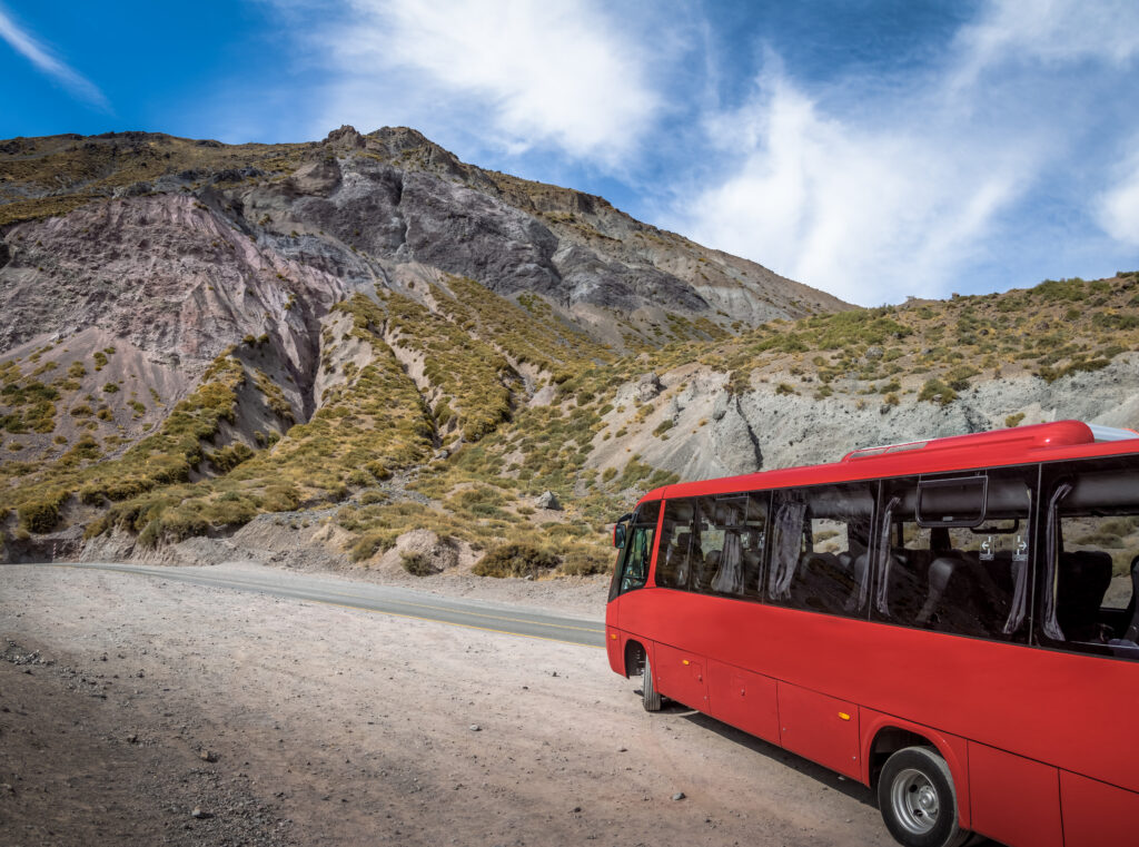 Red bus on a road at Cajon del Maipo Canyon Chile